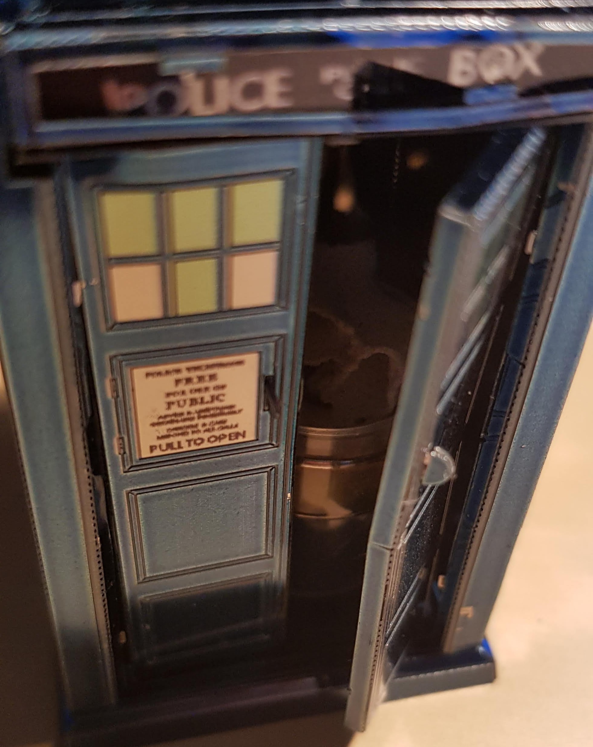 A close up of the same small aluminium TARDIS. The door to go in is slightly ajar and there is an impression of a centre console.