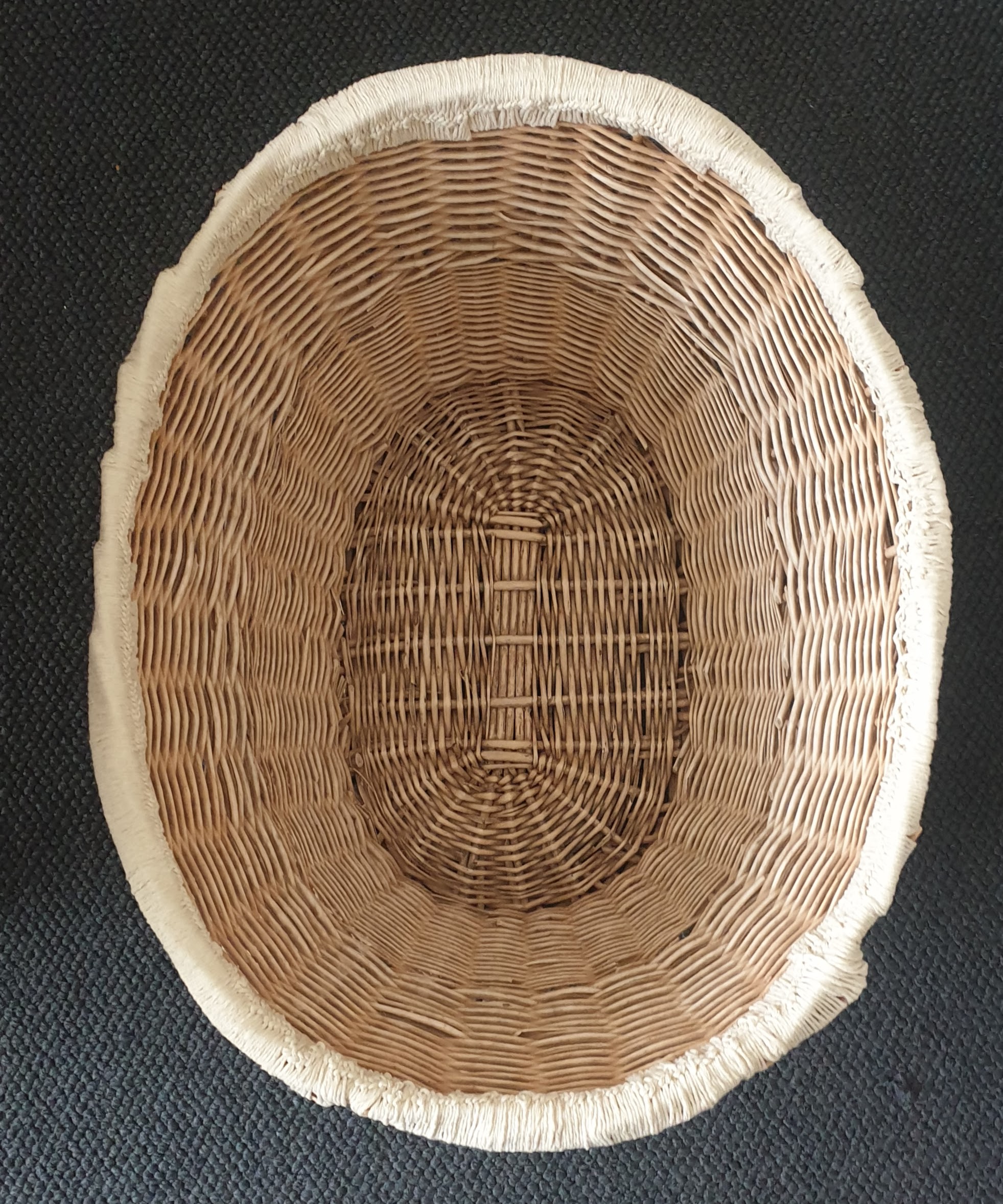 Top-down view of a wicker basket with crochet edging completed in a tan colour. There are no visible handles.
