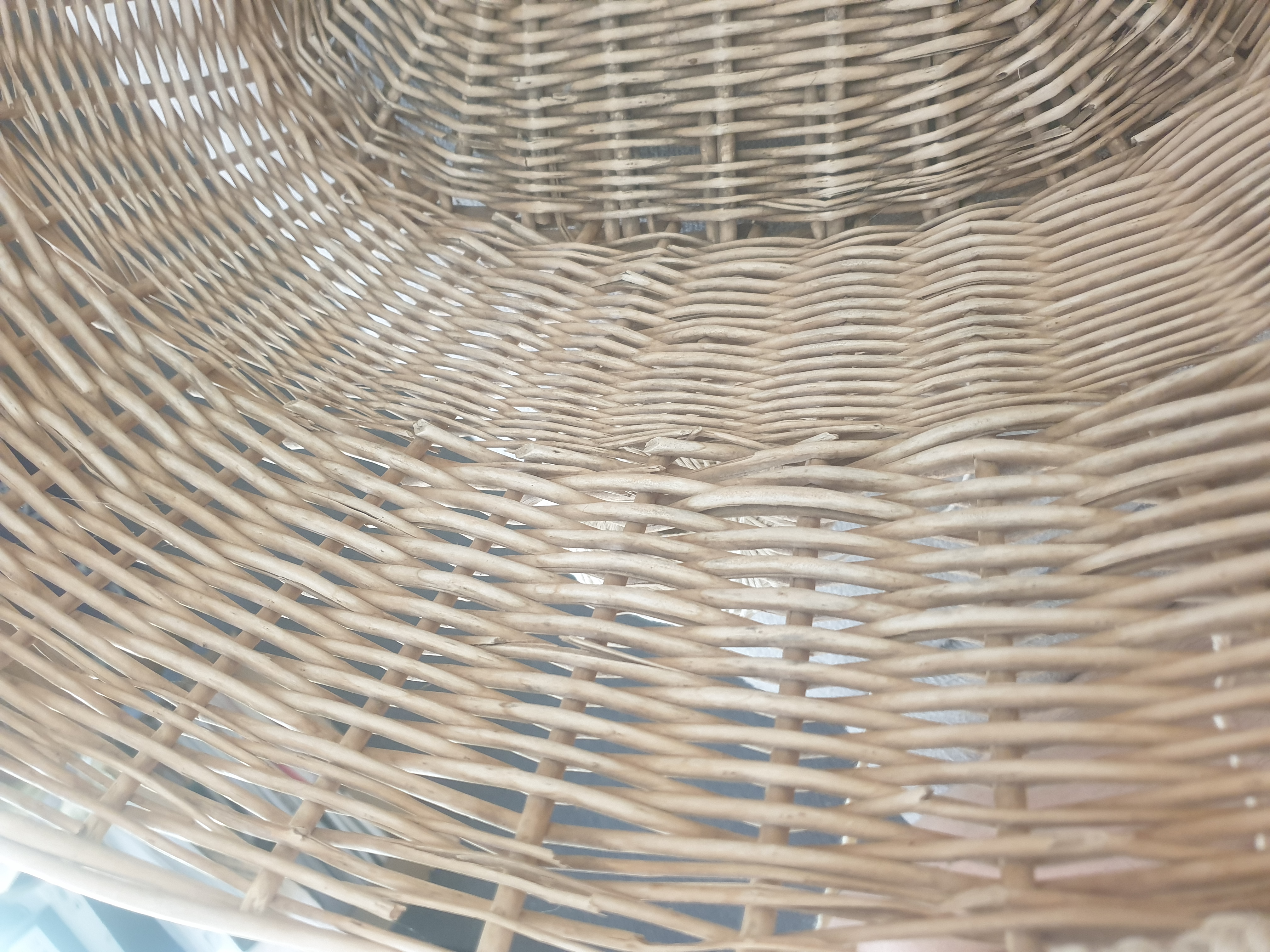 Close up on the inside of a wicker basket which looks damaged around the top edge. There are no visible handles.